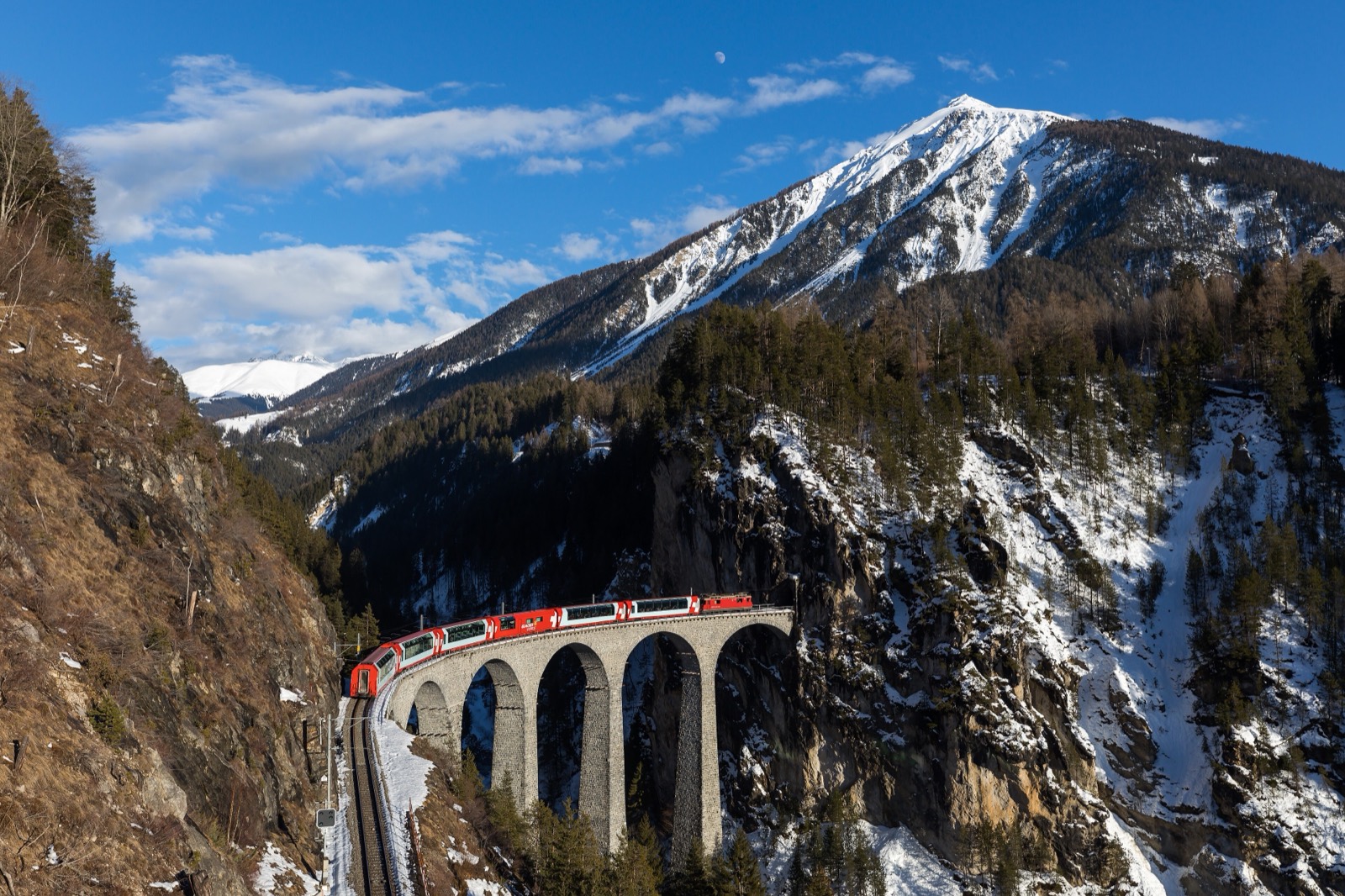 The red Glacier Express crossing the curved Landwasser Viaduct in the Swiss Alps